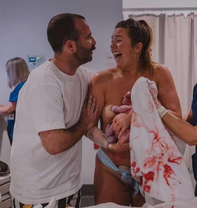 Couple in hospital. Woman has just given birth and holding her new born baby, as couple look at each other